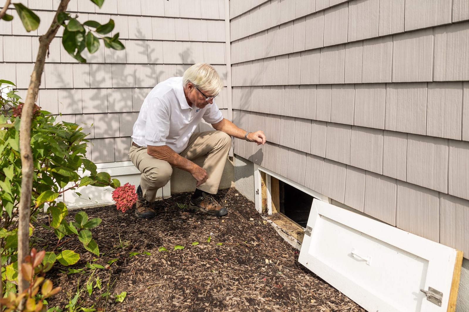An inspector checking a building's foundation and crawlspace access during a pest inspection